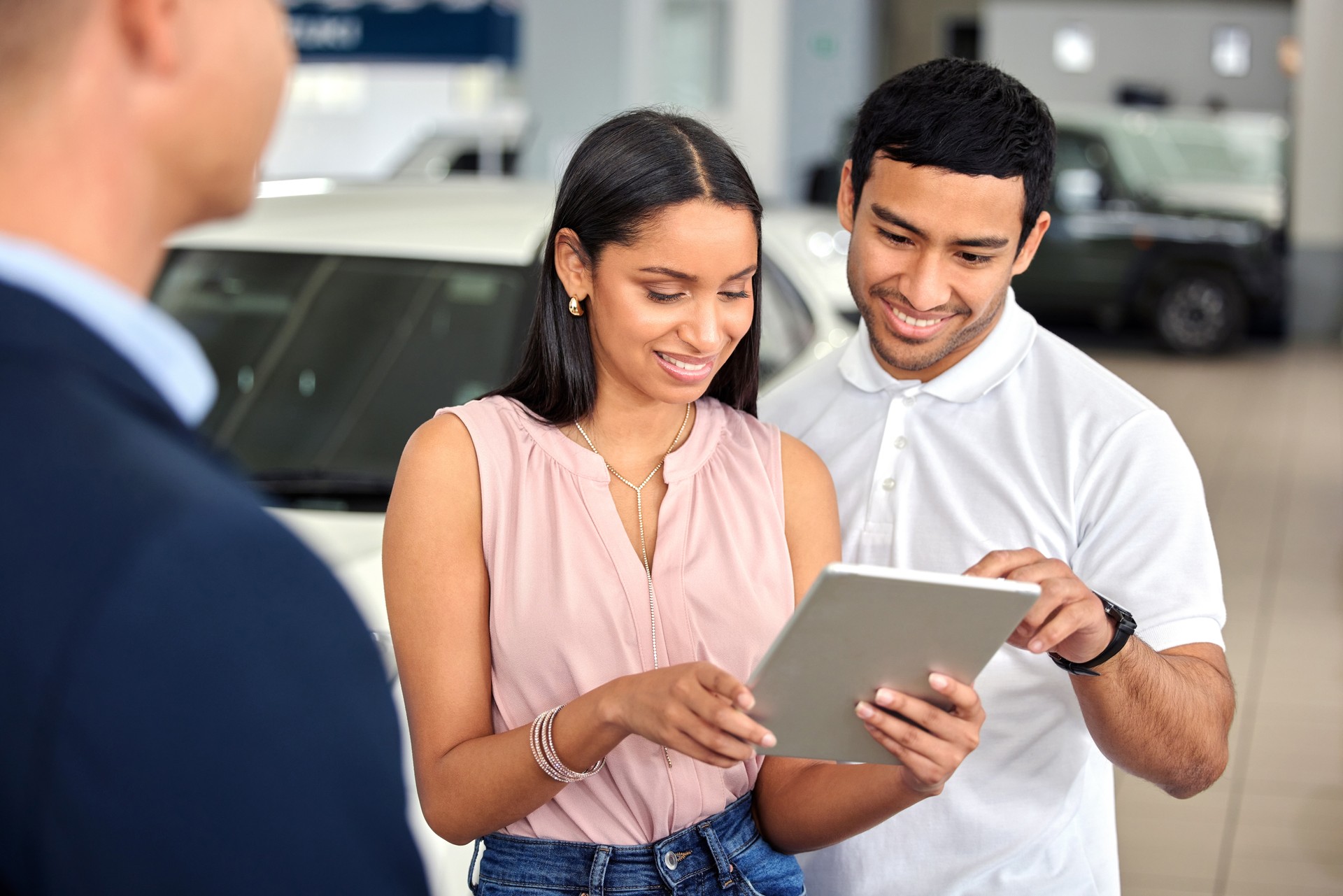 Shot of a car salesman assisting a young couple on the showroom floor