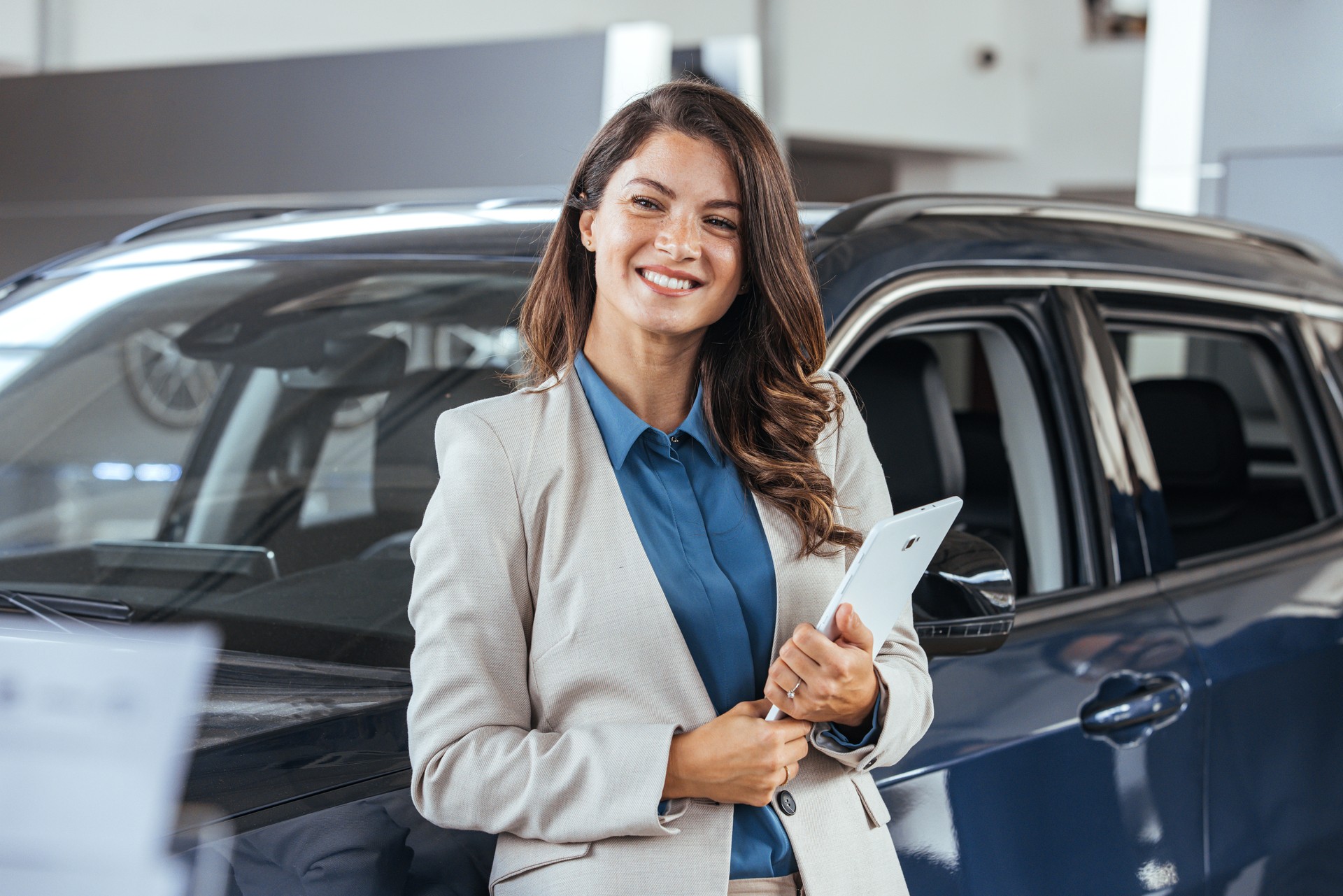 Professional car dealer posing proudly at auto showroom